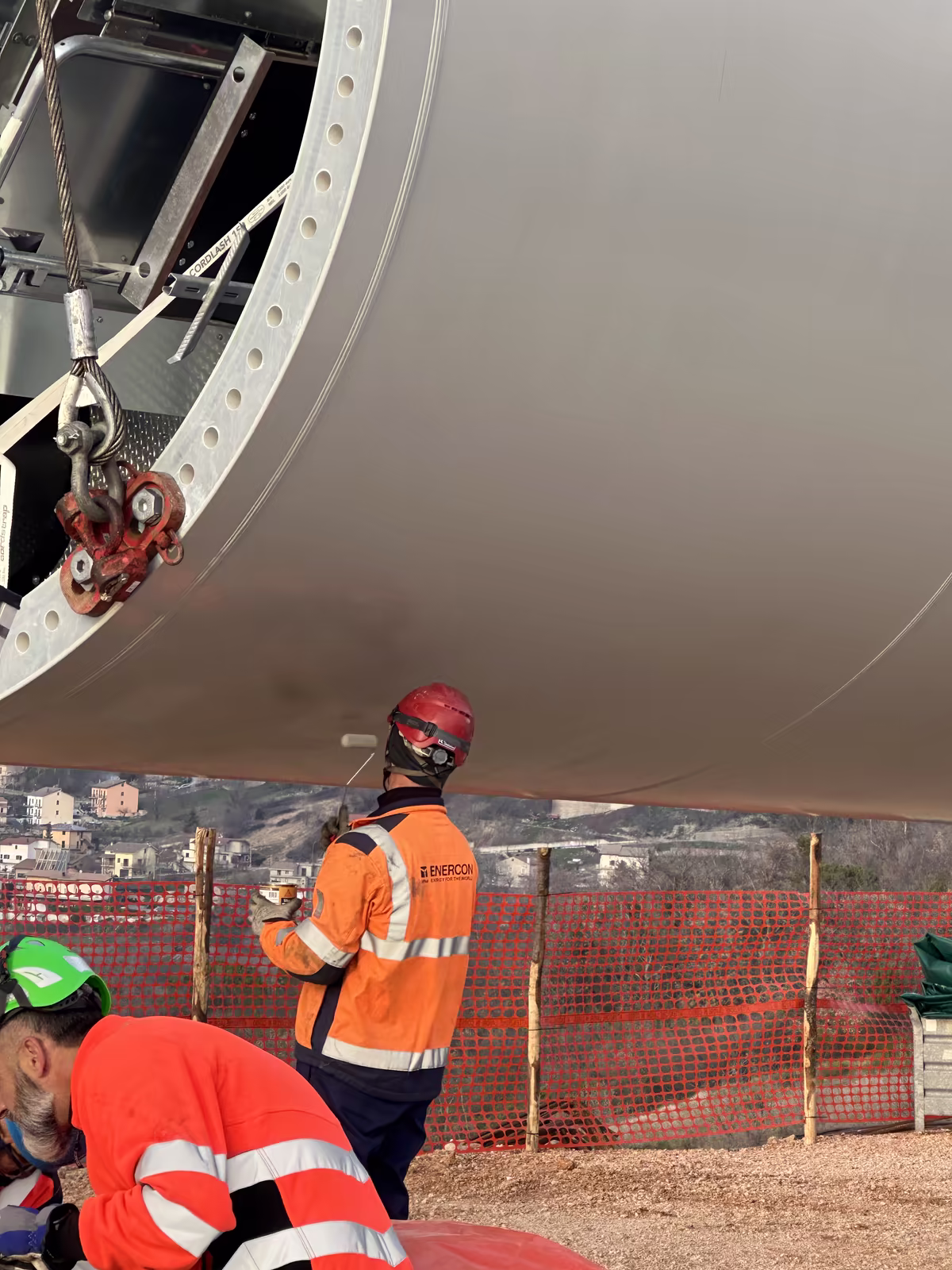 Technicians working beneath a wind turbine component